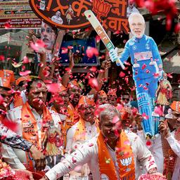 Anhänger von Narendra Modi tragen Pappaufsteller und werfen mit Blütenblättern.