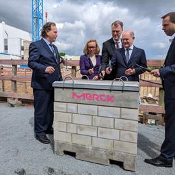 Bundeskanzler Olaf Scholz bei der Grundsteinlegung des neuen Merck-Forschungszentrums. In der Hand hält er einen Hammer. 