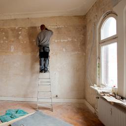 Ein Mann steht auf einer Leiter während eine Altbauwohnung saniert wird (Archivbild: 2012)