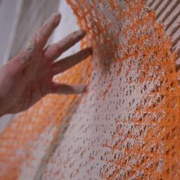 Ein Mann bringt eine Matte aus Glasfasern an eine Wand an.