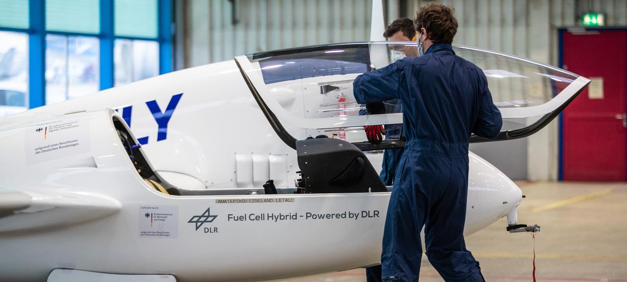 Crewmitglieder befestigen in einem Hangar am Flughafen Stuttgart das Cockpitfenster des Wasserstoff-Brennstoffzellen-Flugzeugs HY4 der Firma H2Fly.