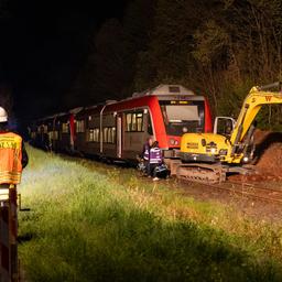 Rettungskräfte stehen an Unfallstelle, wo Zug einen Bagger rammte