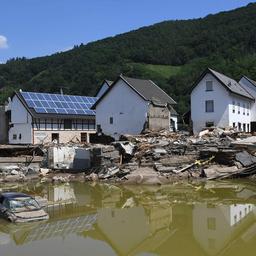Zerstörte Häuser werden im braunen Hochwasser reflektiert.