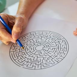 Hand mit Stift beim Labyrinth-Rätsel lösen