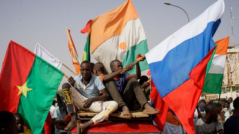 Menschen mit den Flaggen von Burkina Faso, Niger und Russland