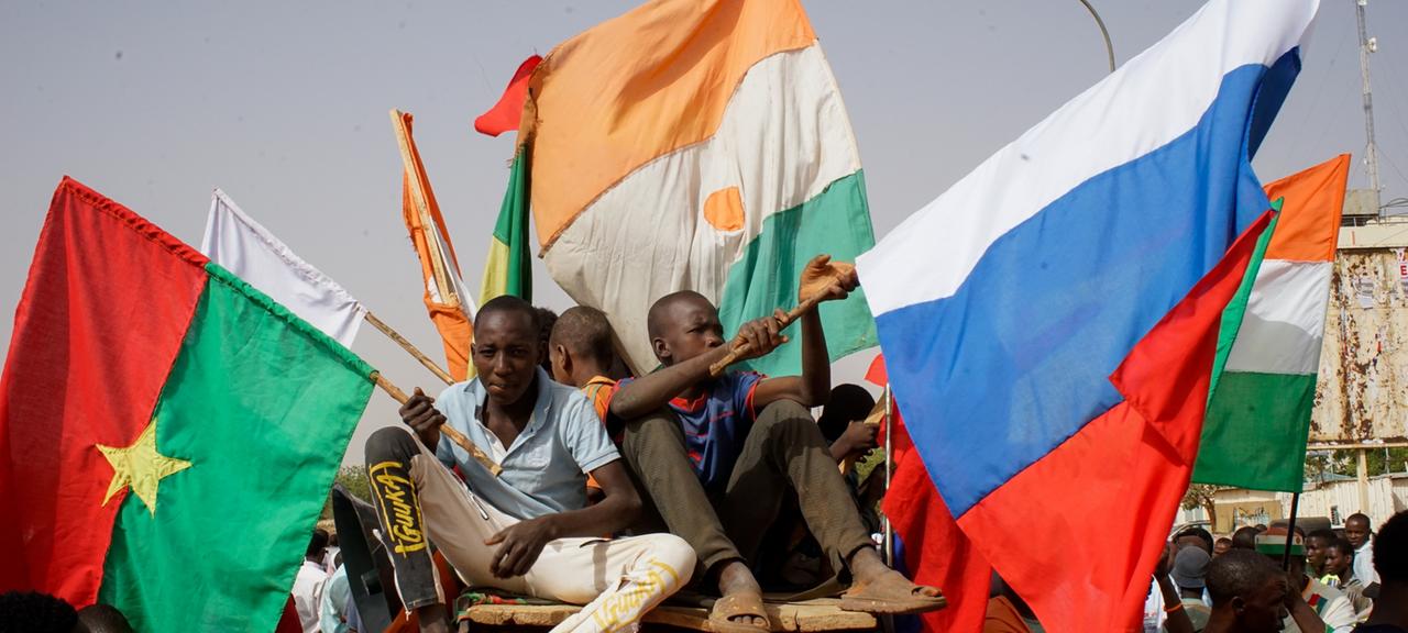 Menschen mit den Flaggen von Burkina Faso, Niger und Russland