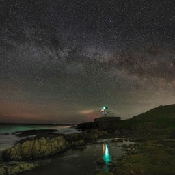 Die Milchstraße wölbt sich über dem Bamburgh Lighthouse in Northumberland an der Nordostküste Englands.