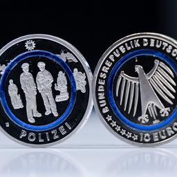 Zwei neue Zehn-Euro-Gedenkmünzen "Polizei" stehen auf einem Tablett.