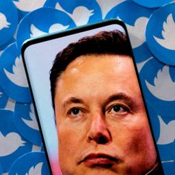 Foto von Elon Musk auf einem Smartphone, das auf Papier-Logos des Kurznachrichtendienstes Twitter liegt