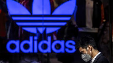 Ein Mann mit Mundschutz geht an einem Adidas-Shop vorbei