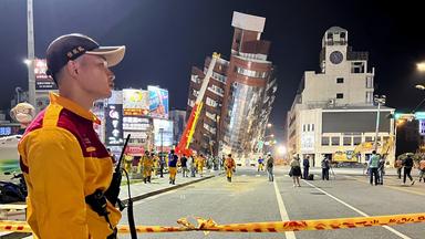 Rettungskräfte stehen um ein schiefes Gebäude in der Stadt Hualien in Taiwan.