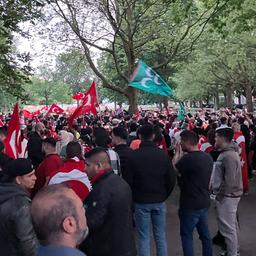 Menschenmenge mit türkischen Flaggen in einem Park.