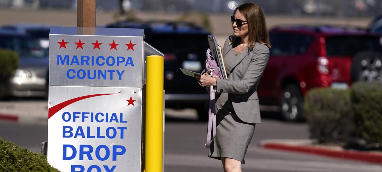 Eine Wählerin wirft einen Stimmzettel in eine Drop Box.