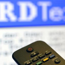 Die Taste ''Teletext'' ist auf einer Fernbedienung für den Fernseher vor einem Videotext (unscharf im Hintergrund) zu sehen.