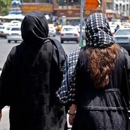 Frauen mit Kopftuch laufen auf einer Straße in Teheran.