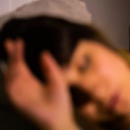 Eine Frau schläft, im Hintergrund steht ein Wecker