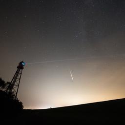 Der helle Schein einer Stadt geht in den Sternenhimmel über.