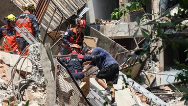 Rettungskräfte, die einem Überlebenden helfen, nachdem er aus einem beschädigten Gebäude in Neu-Taipeh gerettet wurde