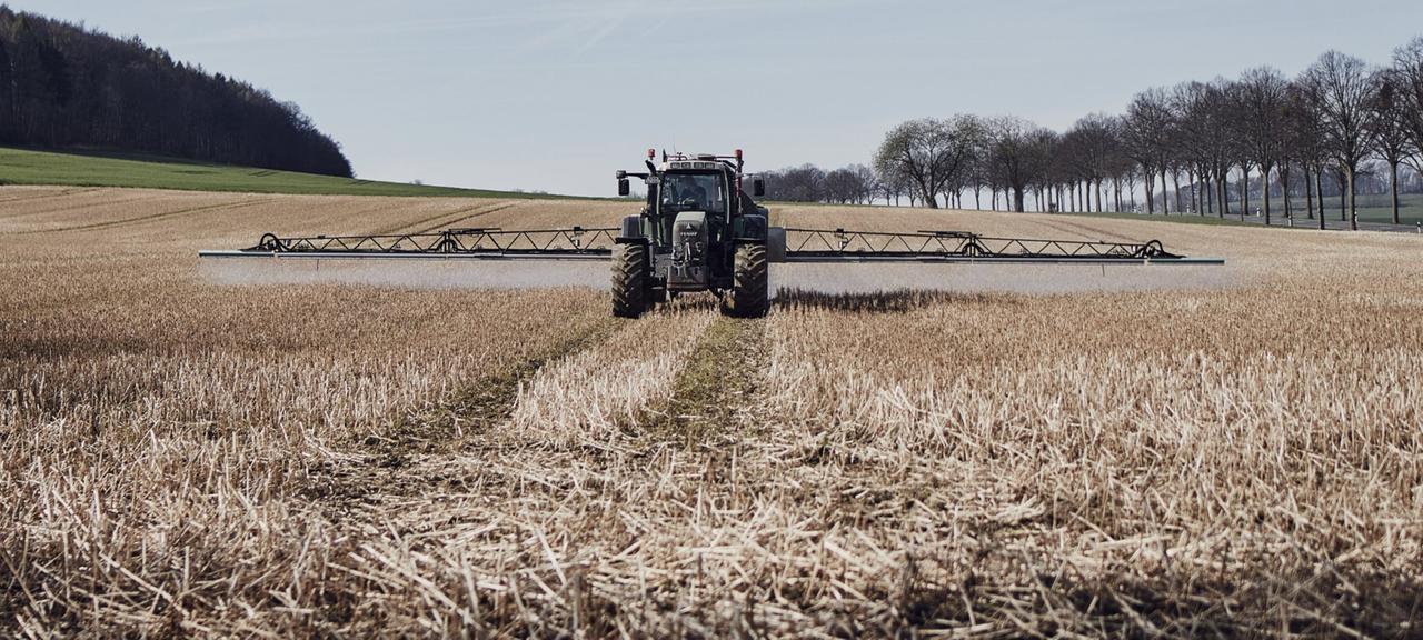 Ein Traktor verteilt Glyphosat auf einem Feld.