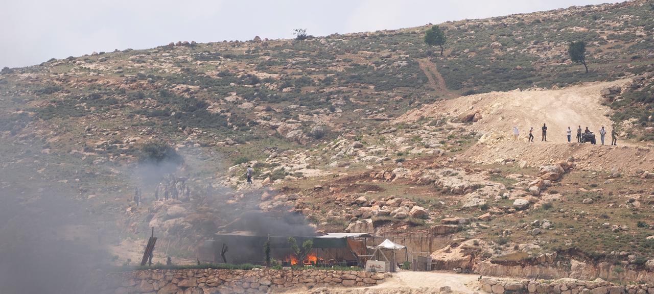 Israelische Siedler versammeln sich in der Nähe von brennenden Häusern palästinensischer Dorfbewohner im Westjordanland.