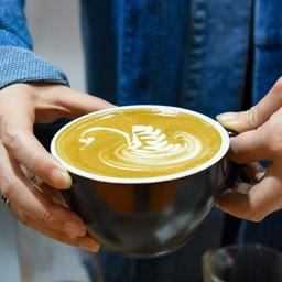 Ein Frau hält eine Tasse Cappuccino in den Händen.