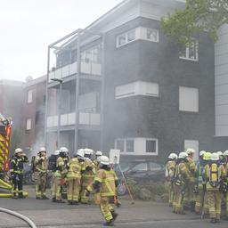 Mehrere Feuerwehrleute stehen vor einem Mehrfamilienhaus in Vechta. Rauch steigt aus dem Gebäude auf.