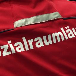 "Sozialraumläufer" steht auf einer roten Jacke.