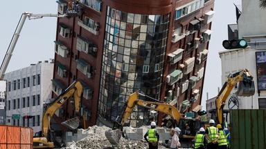 Arbeiter bei Aufräumarbeiten vor einem vom Erdbeben betroffenen Gebäude.