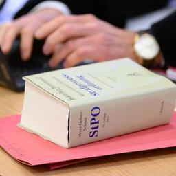 Ein dickes Buch mit der Aufschrift „Strafprozessordnung“ (StPO) liegt bei Gericht neben einem Anwalt