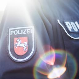 Auf dem mit Gegenlicht fotografiertem Jackenärmel einer Polizeiuniform ist das niedersächsischen Wappen aufgenäht.