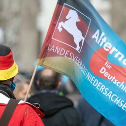 Bei einer Demonstration gegen die Einschränkungen durch die Pandemie-Maßnahmen der Bundesregierung vor dem Brandenburger Tor trägt ein Teilnehmer eine Fahne des niedersächsischen Landesverbandes der Partei AfD.