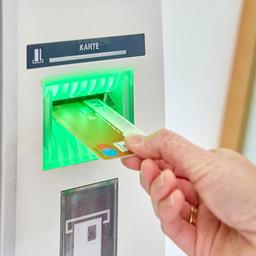 Eine Person steckt Ihre Girocard in einen Geldautomat.