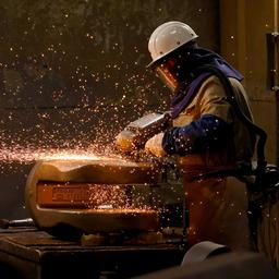 Ein Arbeiter flext ein fertiges Stahlbauteil