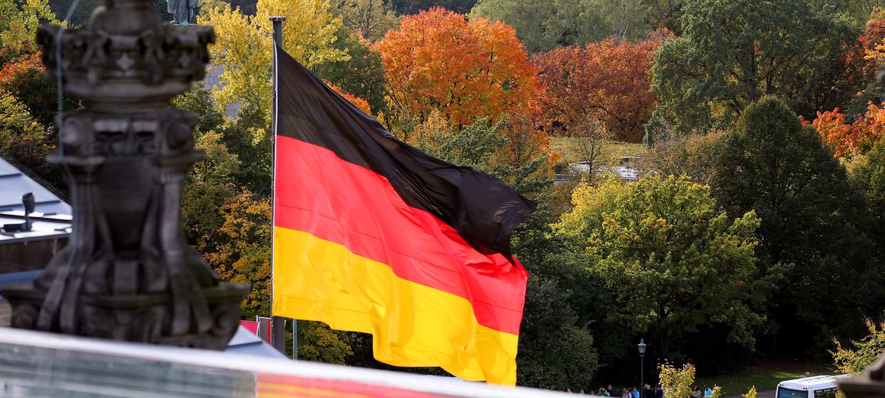 Eine Deutschland-Fahne weht über Bäumen