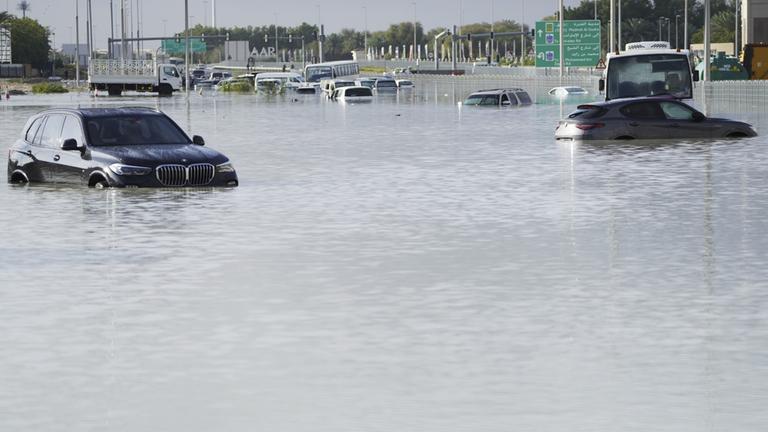 Vereinigte Arabische Emirate, Dubai: Fahrzeuge stehen verlassen im Hochwasser auf einer Hauptstraße in Dubai. 