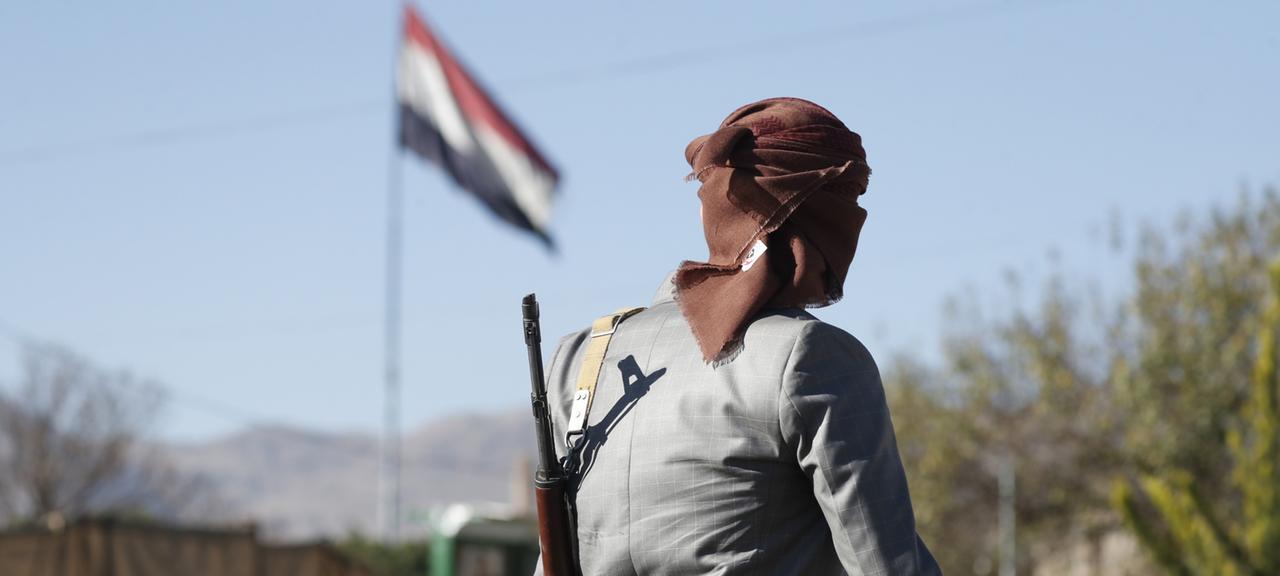 Ein bewaffneter Huthi-Kämpfer geht an einer jemenitischen Fahne vorbei in Sanaa, Jemen.