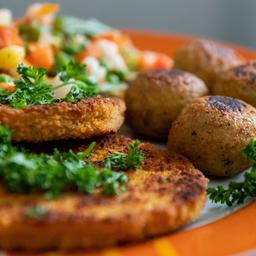 Falafel, vegane Schnitzel und Gemüse liegen auf einem Teller.