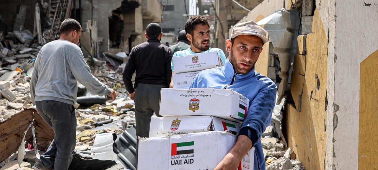 Palästinenser tragen Pakete mit Hilfslieferungen