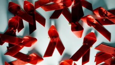 Rote Aids-Schleifen liegen auf einem Tisch. 
