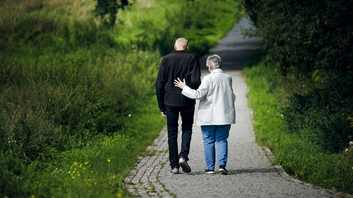 Symbolbild Alter. Ein altes Ehepaar läuft bei einem Spaziergang gemeinsam einen Weg entlang.