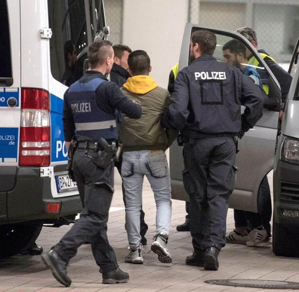 Hand und Fußfesseln trägt ein junger Mann aus Afghanistan, den Polizisten zur Abschiebung zum Flughafen bringen.