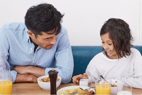 Vater und Tochter sehen sich beim Frühstück zusammen ein Google-Produkt an.