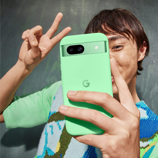 Eine Person posiert vor ihrem Pixel 8a in Aloe für ein Selfie.
