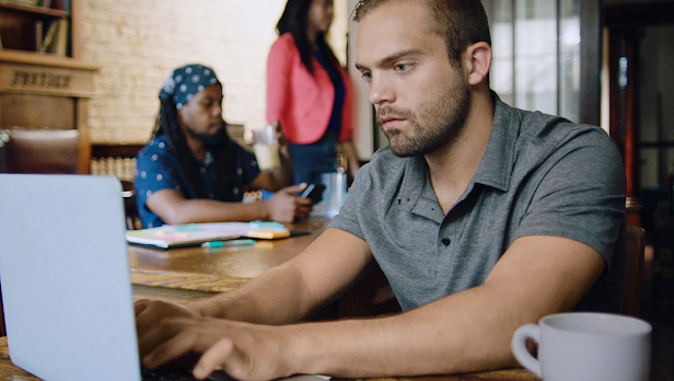 A man sits and intently works on a laptop