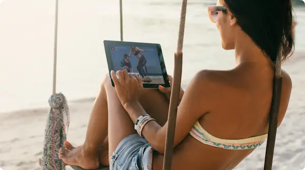 ผู้หญิงกำลังดูแท็บเล็ตบนชายหาด