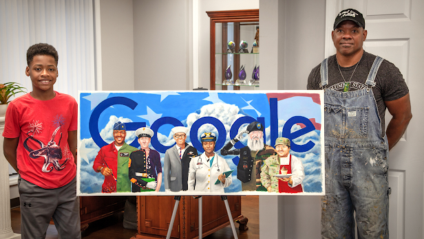 A man and his son stand alongside a print of a Google Doodle depicting six veterans from different branches of the military