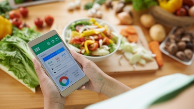 person using a calorie counting app while chopping vegetablesf