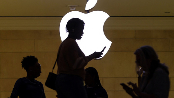 Funktioniert auch dank deutscher Technik: Nutzerin mit iPhone vor dem Markenzeichen des Apple-Konzerns