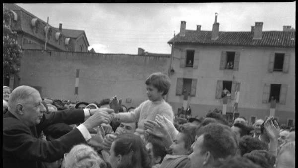 An höchster Stelle sitzt im republikanischen Empfangskomitee ein Kind, als Charles de Gaulle am 17. Mai 1962 in Figeac begrüßt wird. André Cros fotografierte den Präsidenten vor der nach Jean Moulin benannten Schule. Ist der Gaullismus ein System der politischen Mobilisierung oder der Entpolitisierung des Volkes?