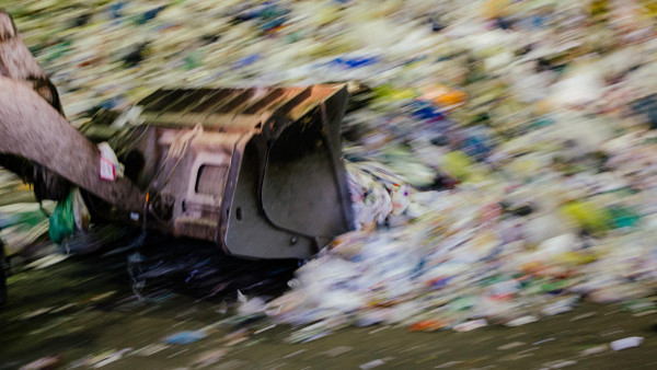 Ein Bagger schaufelt Plastikmüll auf eine Sortieranlage. Ein großer Teil dieses Abfalls wird nicht als Werkstoff recycelt werden, sondern wird verbrannt.